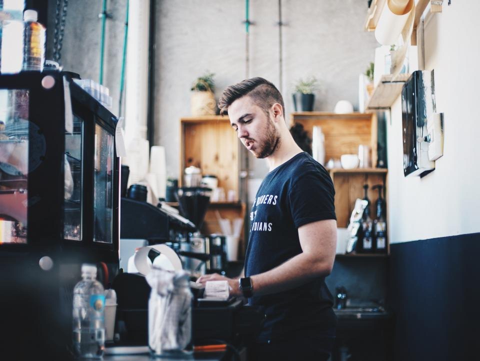 Barista obsluhuje kávovar za barem kavárny